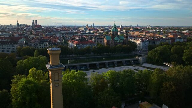 Aerial drone view of Munich, Germany at golden hour featuring M&uuml;ller'sches Volksbad, St. Lukas Church, Isar River, and historic skyline under a vibrant sky. 30 September 2024
