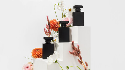 Set of three black perfume bottles on stair risers with flowers all around