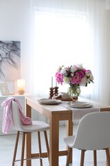 Beautiful table setting with bouquet of peonies in dining room. Interior design