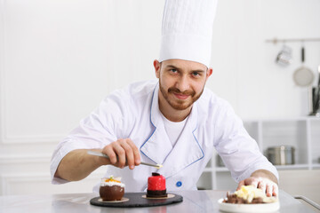 Confectioner decorating delicious dessert with chocolate shaving at table in kitchen