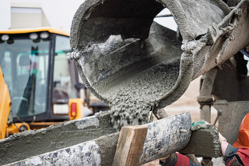 Concrete mixing process at construction site with machinery and workers involved