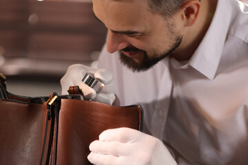 Appraiser with loupe evaluating leather bag indoors