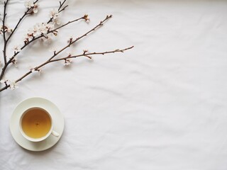 Serene morning teacup with delicate cherry blossoms on white bedding a peaceful spring scene
