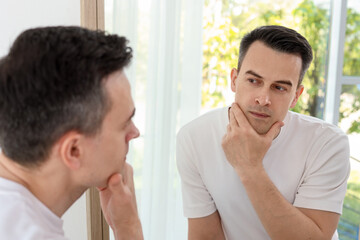 Handsome man after shaving near mirror at home