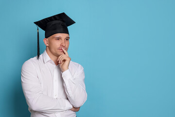 Thoughtful student after graduation on light blue background. Space for text