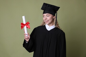Happy student with diploma after graduation on green background