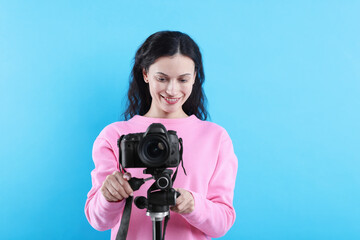 Woman with professional video camera on light blue background