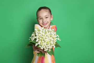 Girl with bouquet of beautiful lily-of-the-valley flowers on green background