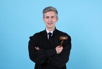 Smiling judge with mallet on light blue background