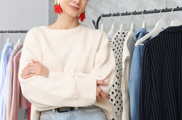 Portrait of professional stylist near clothing rack indoors