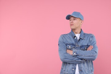 Young man wearing stylish denim baseball hat on pink background, space for text