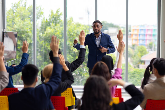 Public speaking training in seminar : African American business man leader in seminar, speaking on business training with group of diverse people company employees in meeting room