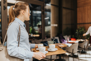 A woman serves coffee on a tray at a bustling outdoor cafe.