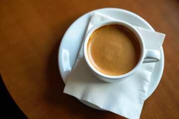 A single cup of coffee sitting on a plain white plate, perfect for breakfast or a morning pick-me-up