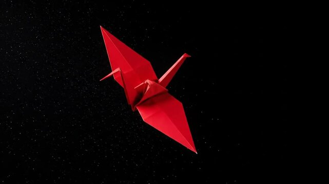 Red origami crane against black background