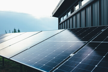 Solar panel installations beside a modern utility building in a green field, generating renewable...