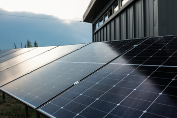 Solar panel installations beside a modern utility building in a green field, generating renewable...