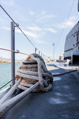 Heavy braided line encircles cleat securing ship at dock. Background includes smooth water surface,...