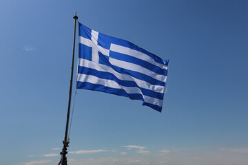 Detailed view of full flag spread outward with steady lines. Pole tilts slightly on ship’s stern,...