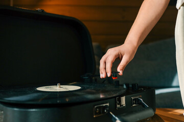 Close-up of hand placing needle on vinyl record on turntable, cozy warm lighting and shallow depth of field enhance vintage atmosphere