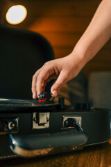 Close-up of hand placing needle on vinyl record on turntable, cozy warm lighting and shallow depth of field enhance vintage atmosphere