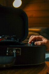 Close-up of hand adjusting volume knob on turntable while vinyl record plays, creating warm...