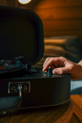 Close-up of hand adjusting volume knob on turntable while vinyl record plays, creating warm...