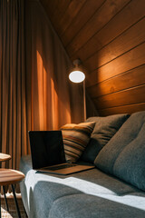 Laptop on a blue couch in a cozy wooden living room with warm natural light, striped pillow, round...
