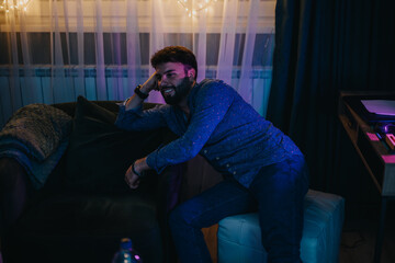A happy young man enjoys a comfortable moment indoors in a warm and atmospheric ambiance,...