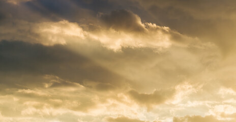 The rays of the evening sun pass through gray and black clouds