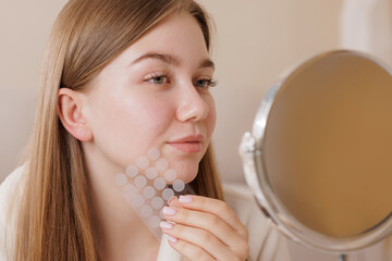 Woman uses hydrocolloid acne patches for clear skin, highlighting beauty care routine and effective...