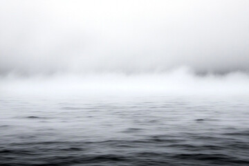 Naklejka premium Fog envelops coastline as waves crash against rocky shore