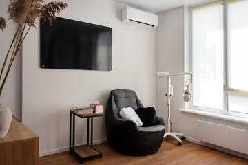 A calm and simple therapy room featuring a cozy chair, a side table, and professional equipment, designed for relaxation and advanced medical procedures.