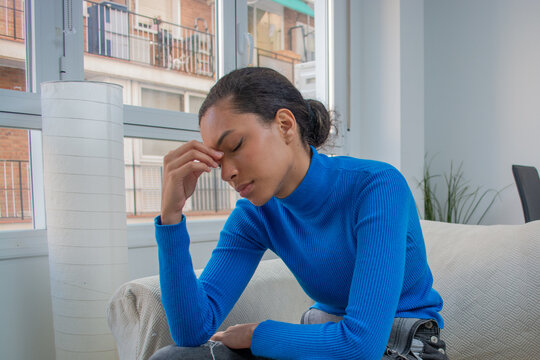 Young woman feeling sick illness stressed sitting ath livingroom and touching her face with hand  eyes closed