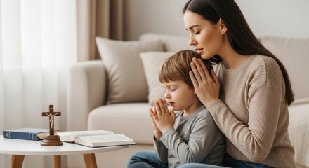 Young caucasian mother and son praying together at home with bible and cross