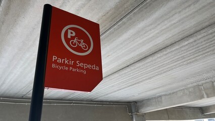Bicycle Parking Sign in Urban Concrete Structure, Red Informational Signage