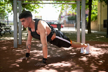 Determined athlete performing plank exercise in calisthenics workout