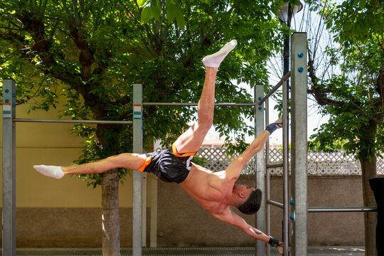 Athlete performing calisthenics human flag on outdoor gym equipment