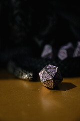 purple role-playing dice, sandwiched within the reels of a black dragon figurine. A subdued fantasy setting, perfect for tabletop, DnD, and role-playing visual effects.