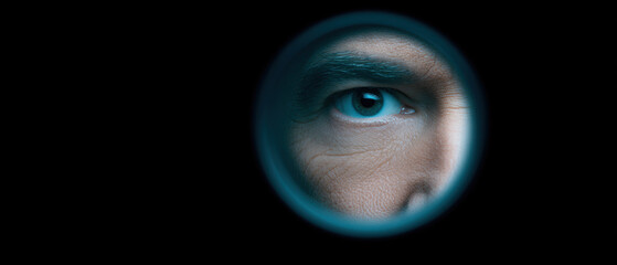 Close up of person eye peering through small circular opening, creating sense of curiosity and intrigue