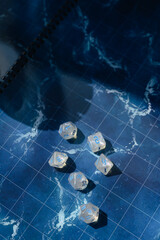 Shimmering RPG dice with blue numbers nestled in the coils of a black dragon figure. A moody...