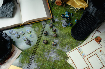Top-down view of a tabletop RPG setup with dice, miniatures, character sheets, a dice tower, and a...