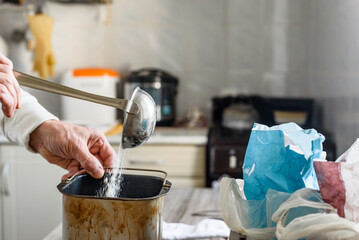 Closeup of male hands putting flour into dough for homemade bread. Baking bread at home with flour,...