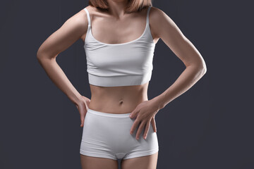 Woman suffering from anorexia on grey background, closeup