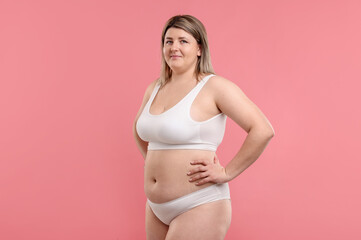 Fototapeta premium Weight loss. Plus size woman in underwear on pink background