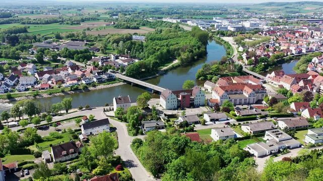 Luftaufnahme von Donauw&ouml;rth mit roten D&auml;chern, historischen Geb&auml;uden und einem markanten Turm, eingebettet in eine gr&uuml;ne Landschaft. Die Stadt bietet eine charmante Kulisse. 