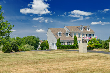 Modern farmhouse home exterior with brick walls sunny autumn day under white clouds and blue sky.
