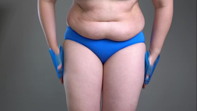 Woman with anti-cellulite massager on gray background, lifting and body care concept