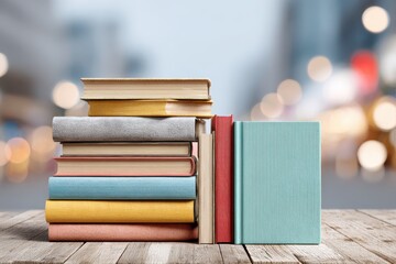A colorful stack of books on a wooden table with blurred background, perfect for a book cover, educational material or library promotion. The books are various colors.