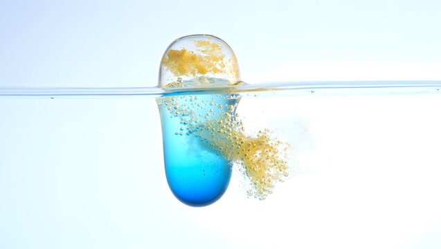 A blue capsule dissolves in water releasing yellow particles creating a dynamic visual effect - Powered by Adobe
